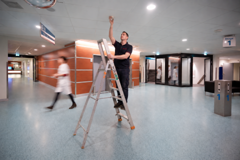 Technicus op ladder in ziekenhuisgang
