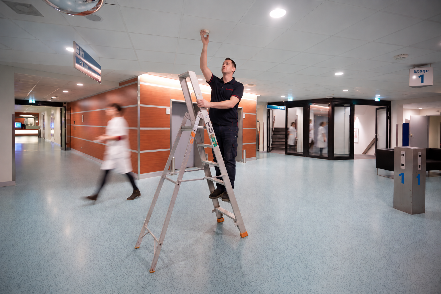 Technicus op ladder in ziekenhuisgang